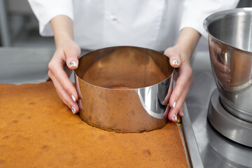 Pastry chef cuts out a cake cake from a biscuit