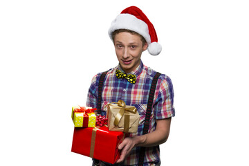 Teenage boy with gift boxes for christmas. Wearing red santa's hat. Isolated on white background.