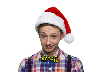 Portrait of teenage boy with christmas santa's hat. Facial expression of contempt or bewilderment. Isolated on white.