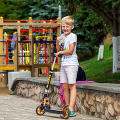 Little boy riding scooter in summer park