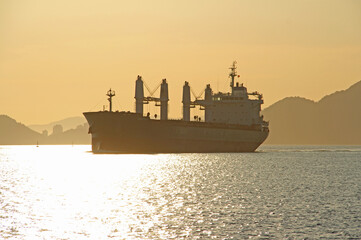 Cargo ship arrives with sunset over the sea