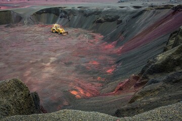 Large quarry for mining and yellow digger. Extraction of red volcanic sand. Iceland.