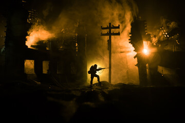 Army sniper with large caliber rifle standing in the fire and smoke. Backlit silhouette, toned image