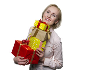Smiling blonde woman holding lot of present boxes on white background. Joyful woman looking at camera.