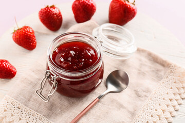 Jar of tasty strawberry jam on table, closeup