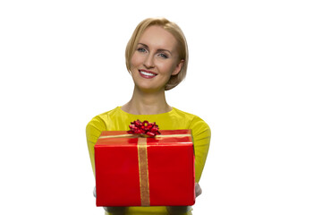 Happy girl gives a gift on white background. Smiling young woman spread his arms forwardly with present. Cheerful young attractive woman.