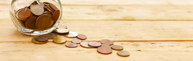 Glass jar with coins, on a wooden background, top view. Finance and investment concept. 