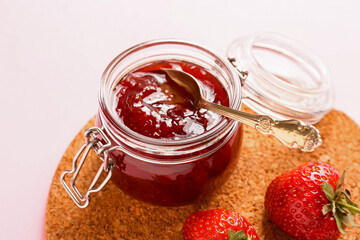 Jar of tasty strawberry jam on color background, closeup