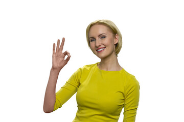 Portrait of young woman in yellow showing okay gesture isolated on the white background. Happy...
