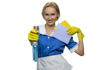 Smiling maid holding rag and pointing spray gun at camera on white background. House keeping concept