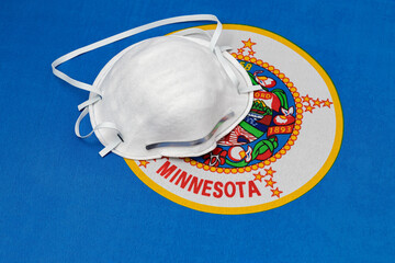 Minnesota state flag and N95 face mask. Concept of state and local government face covering...