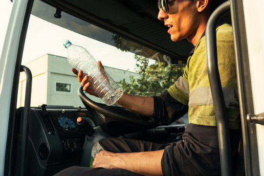 Young truck driver drinking water at work
