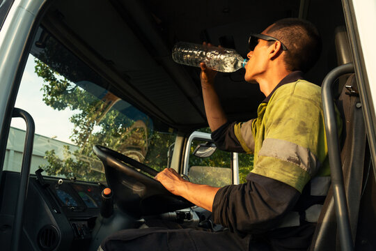 Young truck driver drinking water at work