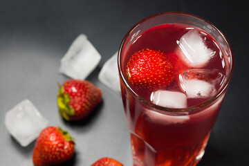 Fruit strawberry a refreshing lemonade with ice on a dark background closeup.