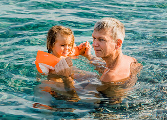 Grandfather and toddler girl having fun in sea