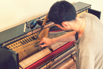 Piano tuning process. closeup of hand and tools of tuner working on grand piano. Detailed view of Upright Piano during a tuning. toned