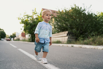 Fototapeta premium Portrait of the cute little boy walking on the road in his neighbourhood