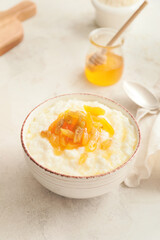 Bowl with boiled rice and fruits on white background