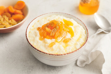 Bowl with boiled rice and fruits on white background
