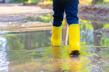the boy jumps in a puddle. a boy in rubber boots. summer fun. game in town. children's entertainment. the article is about the holiday in the city .