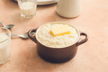 Pot with boiled rice and butter on table
