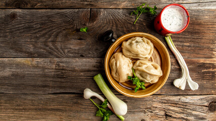 Uzbek prepared boiled Manti or manty dumplings in a traditional bowl on wooden table. banner menu...