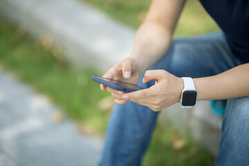 Asian woman sit on skateboard using smartphone in modern city