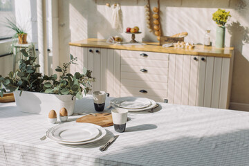 Table served with plates, coffee cups and food for breakfast at modern interior. Family time concept.