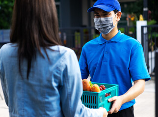 Asian delivery man delivering food, fruit, joice and vegetable to customer home - online grocery shopping service concept