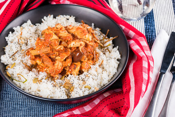 Chicken Cacciatore served on a bed of white rice in a dark round bowl, surrounded by a red napkin