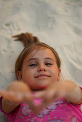 Portrait of a pretty little girl lying on sand