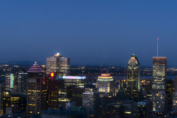 Obraz premium A skyline view of a city illuminated skyscrapers, buildings, and streets taken from a mountain at twilight time, Montreal, QC, Canada