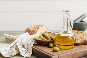 Bottle of tasty olive oil and bread on table