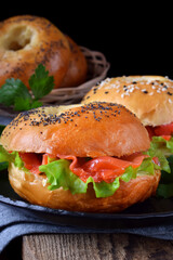 Bagel sandwich with smoked salmon and lettuce salad on black plate