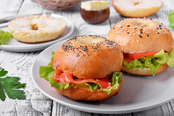 Bagel sandwich with smoked salmon and lettuce salad on ceramic plate