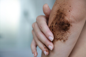 Fototapeta premium DIY Coffee scrub. Beauty skin care. Young woman putting coffee scrub on dry elbow skin.