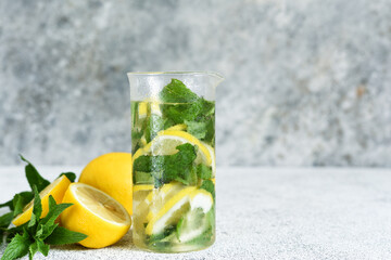 Lemonade with syrup and mint in a glass cup on a concrete background.