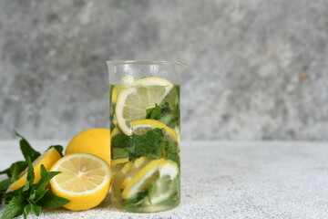 Lemonade with syrup and mint in a glass cup on a concrete background.