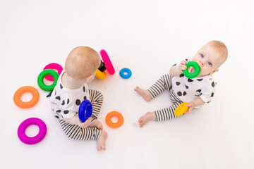 two twin babies 8 months old play on a white isolated background, early development of children up to a year old, a child takes a toy from another, a place for text
