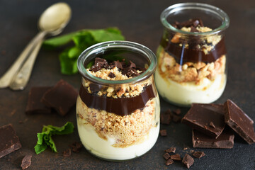 Dessert in a glass. Cheesecake with chocolate in a glass on a dark, concrete background.