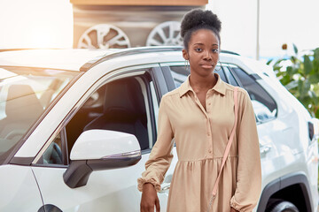 happy young black woman in dealership, beautiful lady came to buy automobile,she liked one of cars...