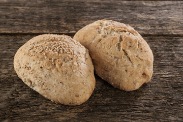 Zwei frische traditionell gebackene Brötchen aus Dinkelmehl auf alten rustikalen Holz