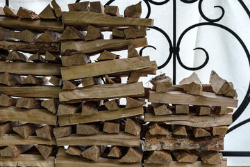 Firewood for the stove and fireplace heating, stacked to dry in a low pile with slots perpendicular to each other.
