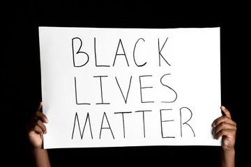 African-American teenage boy with poster on dark background. Stop racism