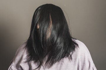 Young Hispanic female posing at the camera with her hair covering her face on gray background