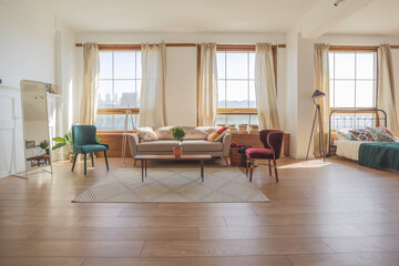 Vintage studio apartment interior in light colors in old style. huge room with large windows with a living room area and a bedroom area. direct sunlight inside.