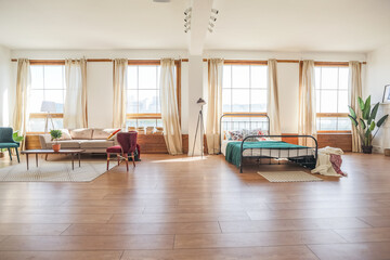 Vintage studio apartment interior in light colors in old style. huge room with large windows with a living room area and a bedroom area. direct sunlight inside.