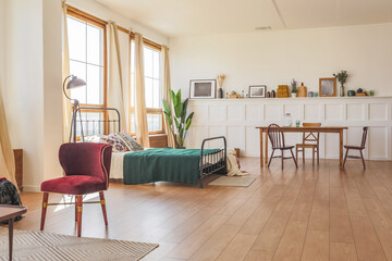 Vintage studio apartment interior in light colors in old style. huge room with large windows with a living room area and a bedroom area. direct sunlight inside.