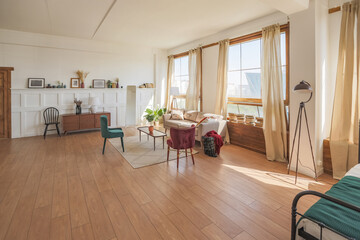 Vintage studio apartment interior in light colors in old style. huge room with large windows with a living room area and a bedroom area. direct sunlight inside.