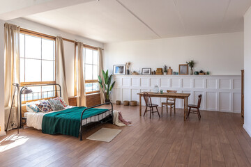 Vintage studio apartment interior in light colors in old style. huge room with large windows with a living room area and a bedroom area. direct sunlight inside.